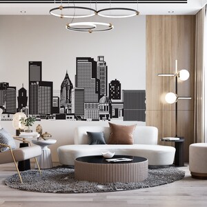 May include: A modern living room with a white sofa, a black and white rug, a coffee table, and a grey armchair. The wall behind the sofa features a black and white cityscape decal.