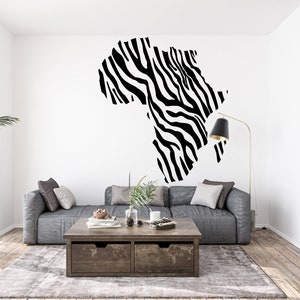 May include: A living room interior with a gray couch, a wooden coffee table, and a large black and white zebra print decal of the continent of Africa on the wall.
