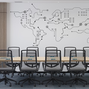 Op de afbeelding: Een moderne vergaderruimte met een grote, witte muur met een zwart-witte wereldkaartontwerp gemaakt van printplaatlijnen. De ruimte heeft een lange houten tafel met zwarte bureaustoelen.