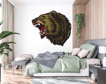 May include: A bedroom interior with a bed, a nightstand, a plant, and a wall decal of a roaring bear head. The bear is brown and has a white background.