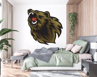 May include: A roaring brown bear head with sharp teeth and a white background. The bear head is a wall decal and is shown in a bedroom setting with a bed, nightstand, and plant.