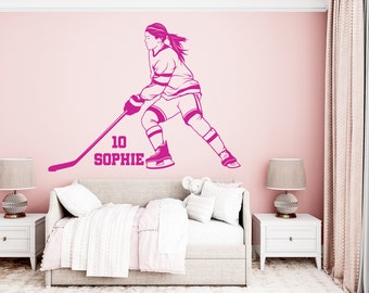 May include: Pink hockey player wall decal with a stick and the text "10 Sophie" on a pink wall in a bedroom setting.