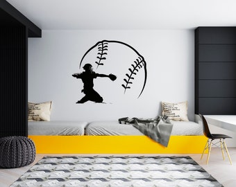 May include: Black and white silhouette of a baseball player catching a ball, with a large baseball graphic behind them. The image is on a white wall in a room with a yellow bed and a black chair.