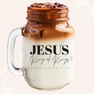 May include: A mason jar filled with iced coffee and ice cubes. The jar has a handle and the text "JESUS King of Kings REVELATION 3:21" is printed on the side.