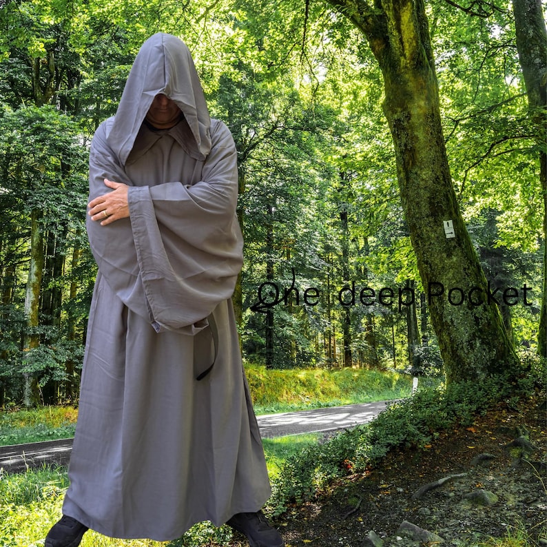 May include: A floor-length, solid grey hooded robe with long, wide sleeves and a deep pocket. The garment features a large, pointed hood that covers the head and drapes over the shoulders, with the text One deep Pocket visible on the right side.