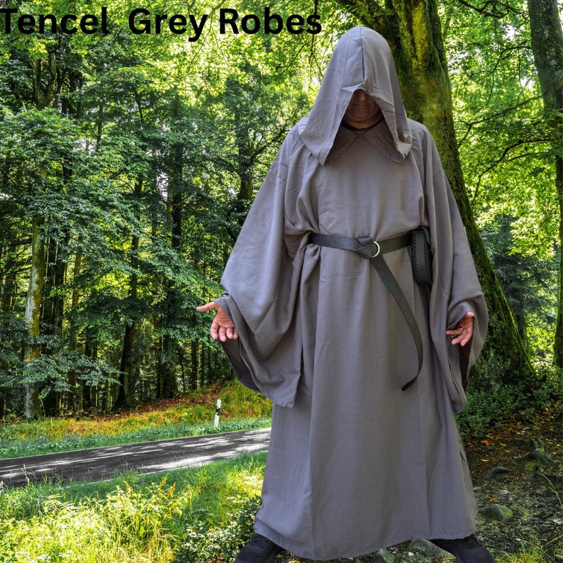May include: A grey hooded robe with long, wide sleeves and a black belt featuring a metal ring buckle. The text Tencel Grey Robes is visible in the upper left corner. The garment is floor-length and features a loose, draped fit throughout.