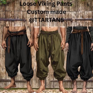 Peut inclure: Trois pantalons amples de style viking, noirs et vert olive, avec une ceinture en cuir marron. Les pantalons ont une taille à cordon et sont faits sur mesure. Le texte de l'image indique "Loose Viking Pants Custom made @TTARTANS."