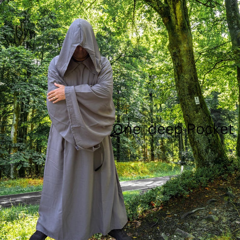 May include: A floor-length, solid grey hooded robe with long, wide sleeves and a deep pocket. The garment features a structured hood that covers the head and drapes over the shoulders, with the text One deep Pocket visible on the right side.