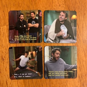 May include: Four square coasters featuring images and quotes from the TV show It's Always Sunny in Philadelphia. The first coaster shows two men with the quote "Dude, if you don't think you're going to hell, you need to take a long look at yourself.". The second coaster shows a man wrapped in a blanket with the quote "Cause I may not be much, Frank, but, uh, I think you'll find that I'm a pretty sweet deal...". The third coaster shows a man in a white shirt and blue shorts with the quote "That - I can go lower. - Bro, that is badass.". The fourth coaster shows a man in a grey hoodie with the quote "Cause I may not be much, Frank, but, uh, I think you'll find that I'm a pretty sweet deal...".