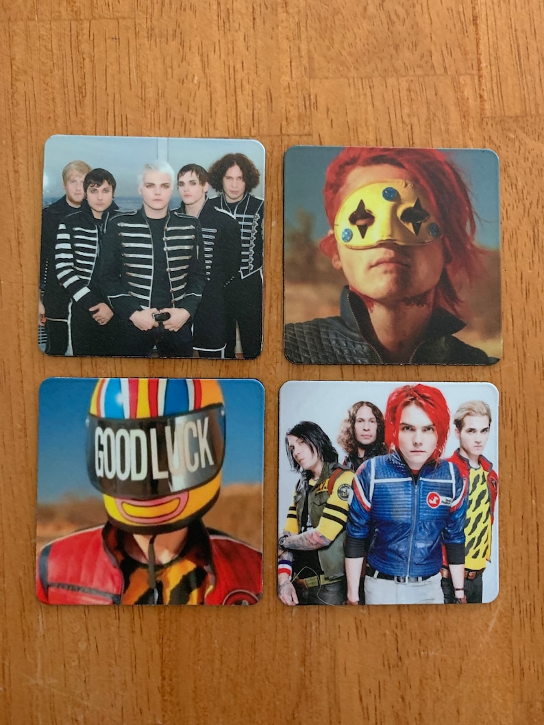 Op de afbeelding: Vier vierkante magneten met een band. De eerste magneet toont een groep van vijf personen die zwart-wit gestreepte shirts dragen. De tweede magneet toont een persoon die een geel masker met zwarte diamanten draagt. De derde magneet toont een persoon die een gele helm draagt met de woorden "Good Luck" erop. De vierde magneet toont een groep van vier personen die kleurrijke kleding dragen.