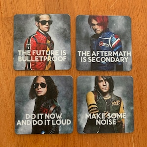 Op de afbeelding: Vier vierkante onderzetters met zwart-witafbeeldingen van een band. Elke onderzetter heeft een ander bandlid en een citaat. De citaten zijn "The future is bulletproof", "The aftermath is secondary", "Do it now and do it loud" en "Make some noise".