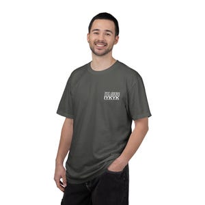 May include: Dark gray t-shirt with the text "FIVE ARROWS IYKYK" printed in white on the upper left chest. The shirt is a short-sleeved crew neck style.