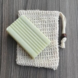 Puede incluir: Una bolsa de malla blanca con cierre de cord&oacute;n y una barra de jab&oacute;n verde en su interior. La bolsa est&aacute; hecha de fibras naturales y est&aacute; dise&ntilde;ada para contener jab&oacute;n mientras se enjabona.