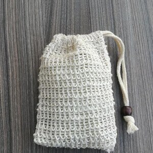 Puede incluir: Una bolsa de cord&oacute;n de malla blanca con un cierre de madera. La bolsa est&aacute; hecha de un material fino y tejido y est&aacute; dise&ntilde;ada para contener objetos peque&ntilde;os.