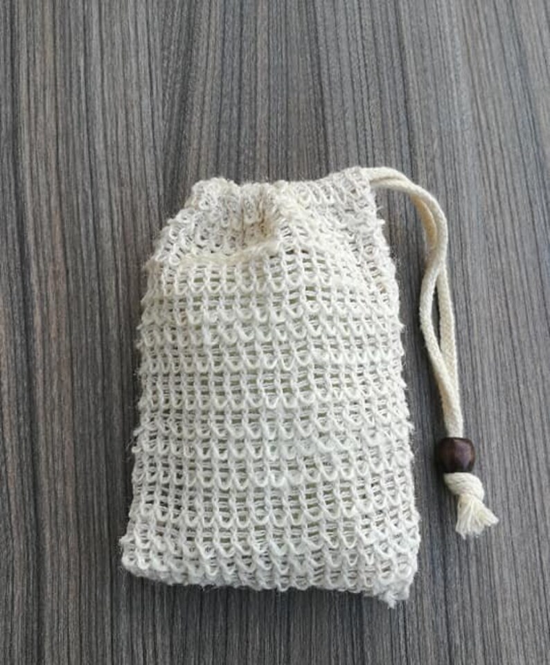 Puede incluir: Una bolsa de cord&oacute;n de malla blanca con un cierre de madera. La bolsa est&aacute; hecha de un material fino y tejido y est&aacute; dise&ntilde;ada para contener objetos peque&ntilde;os.