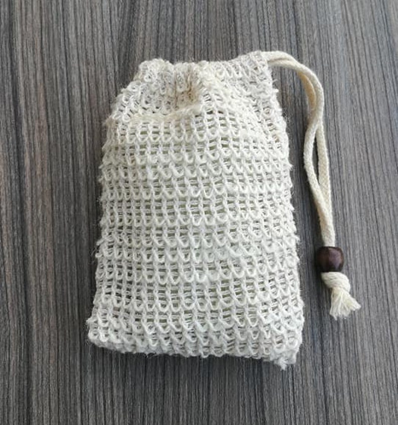 Puede incluir: Una bolsa de cord&oacute;n de malla blanca con una cuenta de madera en el cord&oacute;n. La bolsa est&aacute; hecha de un material fino y tejido y est&aacute; dise&ntilde;ada para contener jab&oacute;n u otros art&iacute;culos peque&ntilde;os.