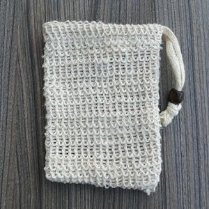 Puede incluir: Una bolsa de malla blanca con cierre de cord&oacute;n y un bot&oacute;n de madera. La bolsa est&aacute; hecha de un material fino y tejido y est&aacute; dise&ntilde;ada para contener objetos peque&ntilde;os.