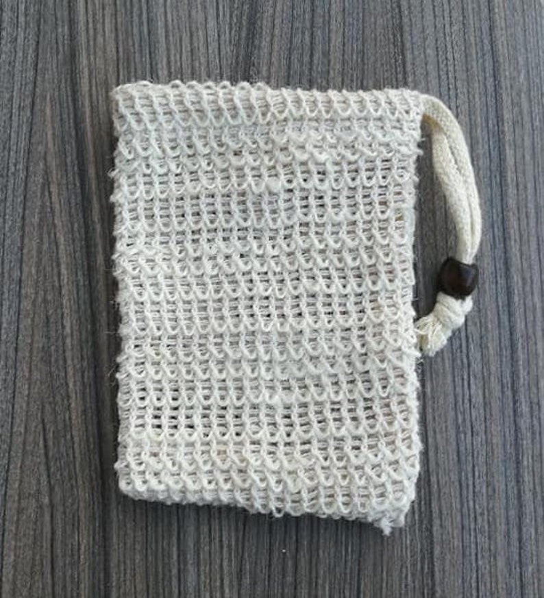Puede incluir: Una bolsa de malla blanca con cierre de cord&oacute;n y un bot&oacute;n de madera. La bolsa est&aacute; hecha de un material fino y tejido y est&aacute; dise&ntilde;ada para contener objetos peque&ntilde;os.