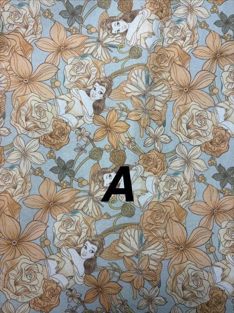 Pu&ograve; includere: Tessuto fantasia con un personaggio dei cartoni animati, fiori e farfalle nei toni del beige, crema e azzurro. La lettera "A" &egrave; stampata in nero sul tessuto.