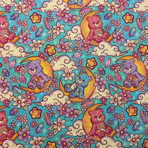 May include: A repeating pattern featuring cartoon bears sitting on crescent moons, surrounded by flowers, stars, clouds, and crystals. The bears are in various colors, including pink, blue, and purple, set against a teal background.