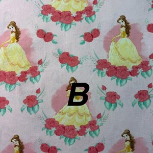 Pu&ograve; includere: Tessuto rosa con un motivo ripetuto di una principessa in abito giallo, circondata da rose rosse e foglie verdi. La principessa ha i capelli castani ed &egrave; ambientata su uno sfondo rosa con un disegno circolare rosa pi&ugrave; chiaro.