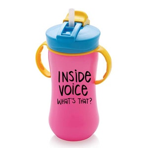 May include: Pink plastic sippy cup with yellow handles and a blue lid. The cup has a straw and says "Inside Voice What's That?" on the front.