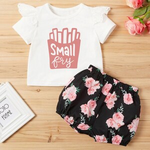 May include: A white short-sleeved t-shirt with a pink graphic of french fries and the text "Small fry". The shirt is paired with black shorts with a pink floral print.