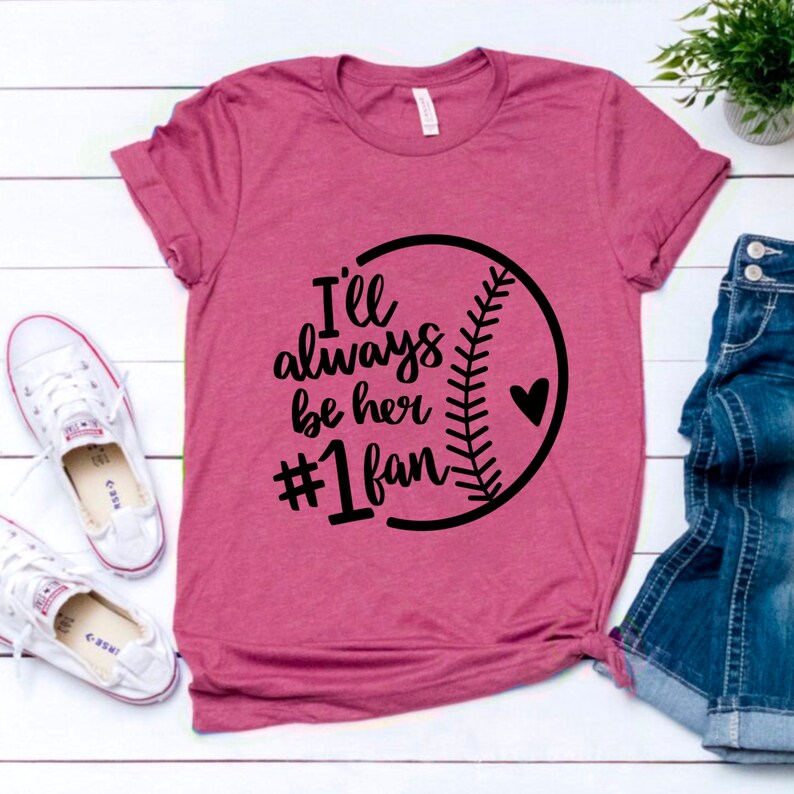 May include: A pink t-shirt with a black baseball graphic and the text "I'll always be her #1 fan".
