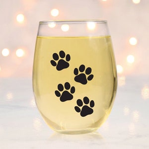 May include: A clear glass wine glass with a design of four black paw prints on the side.