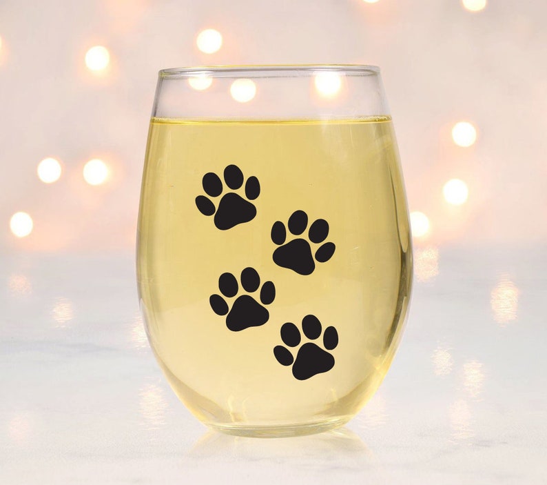 May include: A clear glass wine glass with a design of four black paw prints on the side.