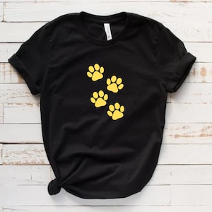 May include: Black t-shirt with four yellow paw prints on the front.