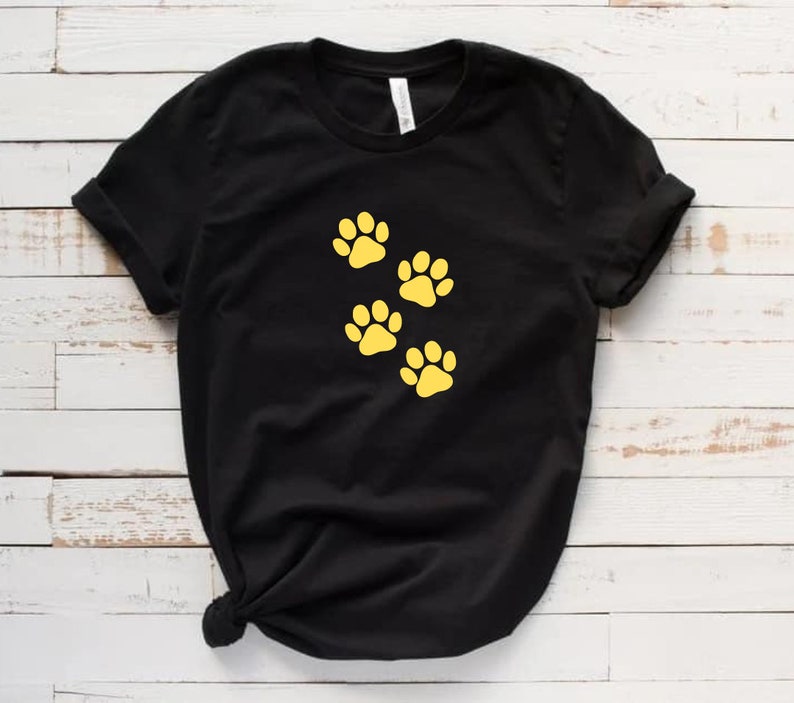 May include: Black t-shirt with four yellow paw prints on the front.
