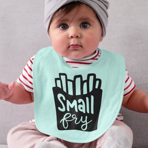 May include: A baby wearing a light blue bib with a black graphic of french fries and the text "Small fry". The baby is wearing a red and white striped shirt and a gray hat.