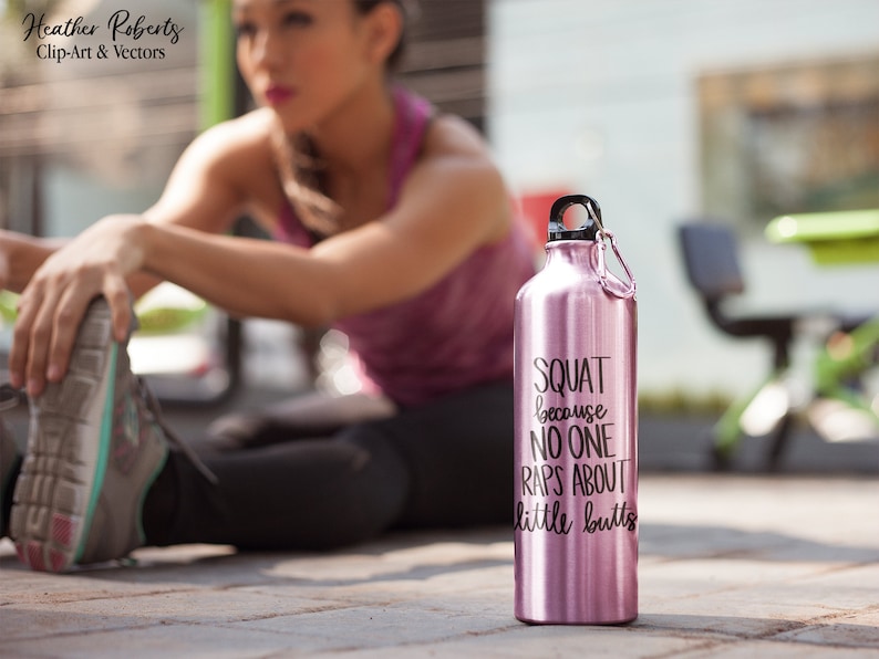 K&ouml;nnte beinhalten: Eine rosafarbene Edelstahl-Trinkflasche mit schwarzem Deckel und Karabinerhaken. Auf der Flasche steht in schwarzer Schrift "SQUAT because NO ONE RAPS ABOUT little butts". Die Flasche steht auf einer Betonoberfl&auml;che.