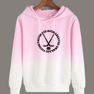 May include: Pink and white ombre hoodie with a black circle graphic featuring hockey sticks and the text "Outmaneuver. Outskate.  Embrace. Victory."