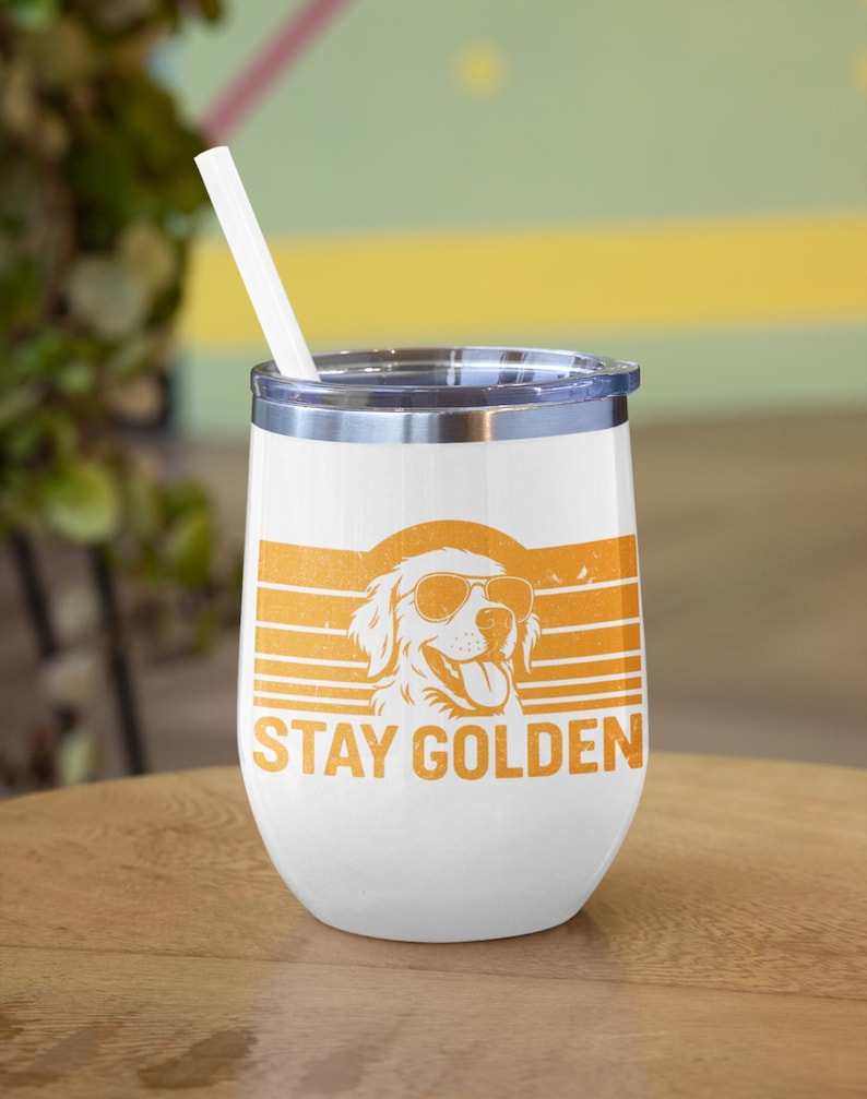 May include: White insulated tumbler with a silver rim and a white straw. The tumbler features an orange graphic of a Golden Retriever wearing sunglasses, with the words "STAY GOLDEN" below the dog.