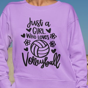 May include: Purple sweatshirt with the text "Just a girl who loves volleyball" in black lettering with a volleyball graphic.