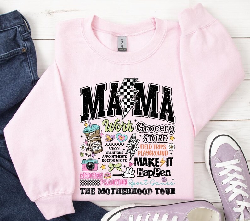 May include: Pink sweatshirt with a black and white graphic that says "Mama Work Grocery Store Field Trips Playground Make It Happen The Motherhood Tour".