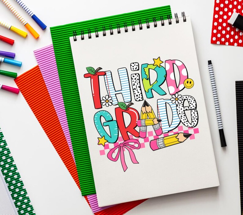 Puede incluir: Una libreta blanca con espiral y un dise&ntilde;o colorido que dice "Tercer Grado". La libreta est&aacute; rodeada de l&aacute;pices de colores y otros &uacute;tiles escolares.