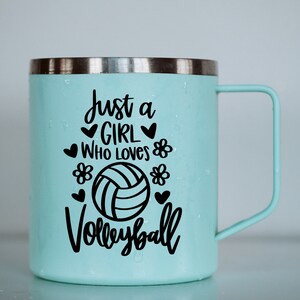 May include: A light blue stainless steel travel mug with a black vinyl decal that reads "Just a girl who loves volleyball" with a volleyball graphic and hearts and flowers.