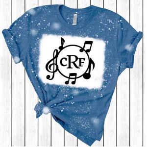 May include: A blue denim t-shirt with a white bleach design featuring a circle with the initials "CRF" and musical notes around it.