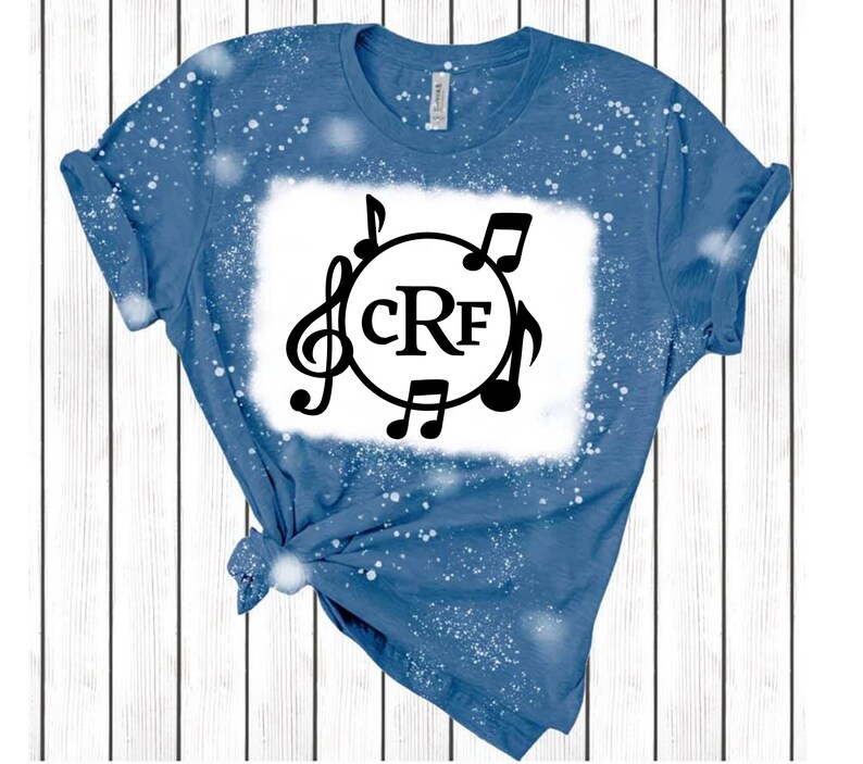 May include: A blue denim t-shirt with a white bleach design featuring a circle with the initials "CRF" and musical notes around it.