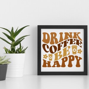 May include: A black framed print with the text "Drink Coffee Be Happy" in brown and gold lettering with stylized coffee cups and flowers.