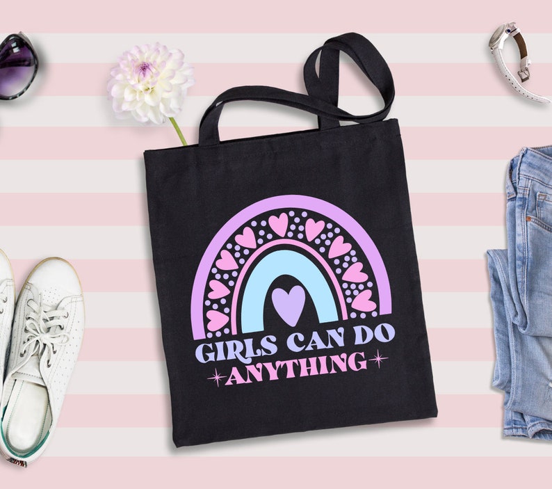 May include: Black tote bag with a rainbow design and the text "Girls Can Do Anything" in pink and blue lettering. The rainbow is decorated with pink hearts.