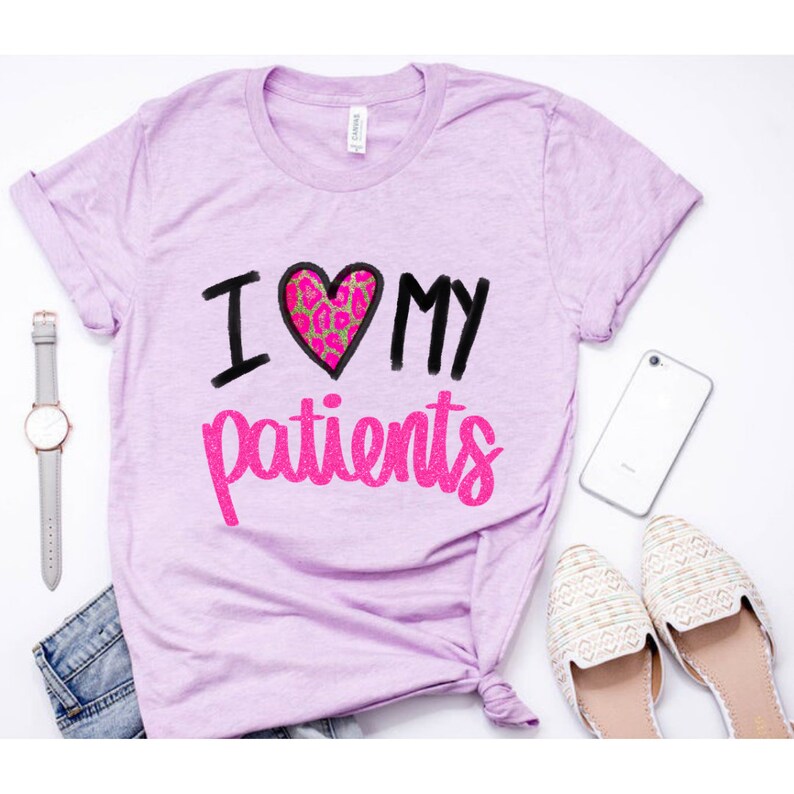 Puede incluir: Una camiseta de color morado claro con el texto "I love my patients" en letras negras y brillantes de color rosa. El coraz&oacute;n es rosa con un dise&ntilde;o de estampado de leopardo.