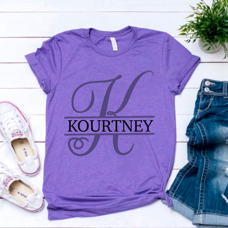 May include: Purple t-shirt with a split monogram design. The letter "K" is in a script font and the name "Kourtney" is printed below the letter.