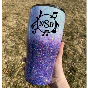 May include: A white and purple glitter tumbler with a black circle design featuring the initials "NSR" and musical notes.