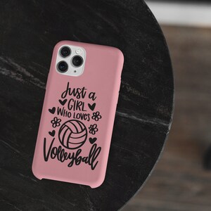 May include: Pink phone case with a black design that says "Just a girl who loves volleyball" with a volleyball graphic.