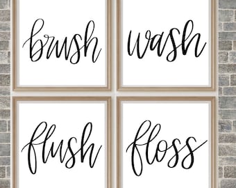 May include: Four framed prints with black calligraphy on a white background. The prints read "brush", "wash", "flush", and "floss".