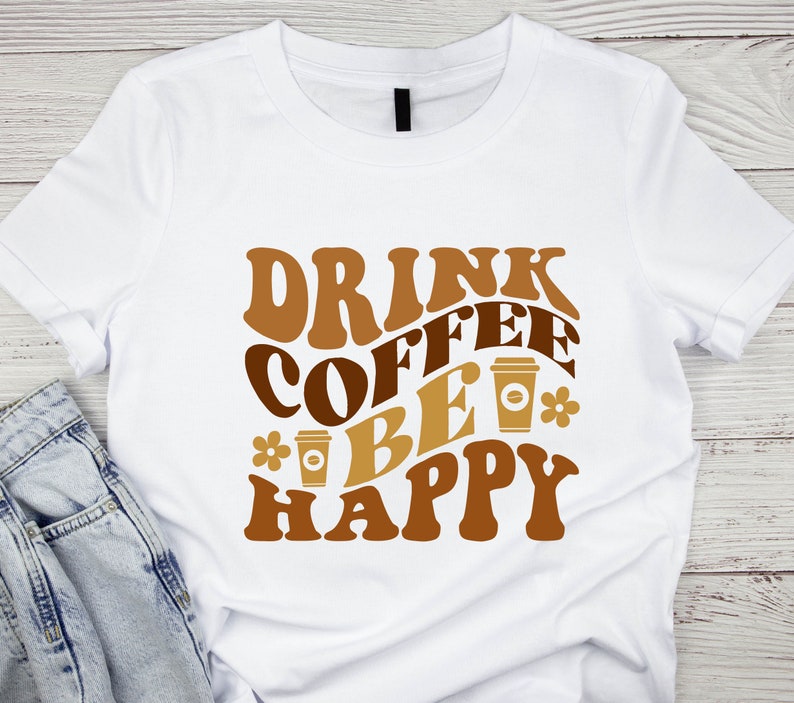 May include: White t-shirt with brown text that reads "Drink Coffee Be Happy" with a coffee cup graphic.